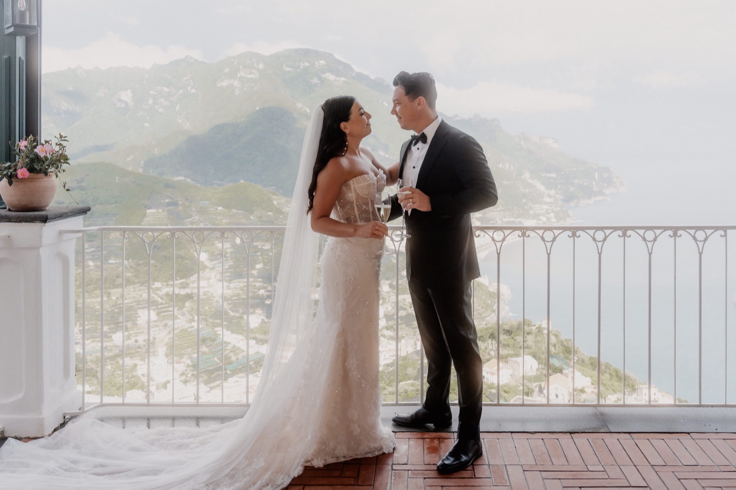 A couple toasting on the terrace of Palazzo Avino in Ravello, with the Amalfi Coast behind them