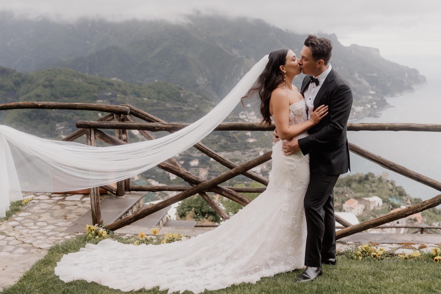 A couple kissing with the bride's long veil blowing across the lawn at Palazzo Avino in Ravello