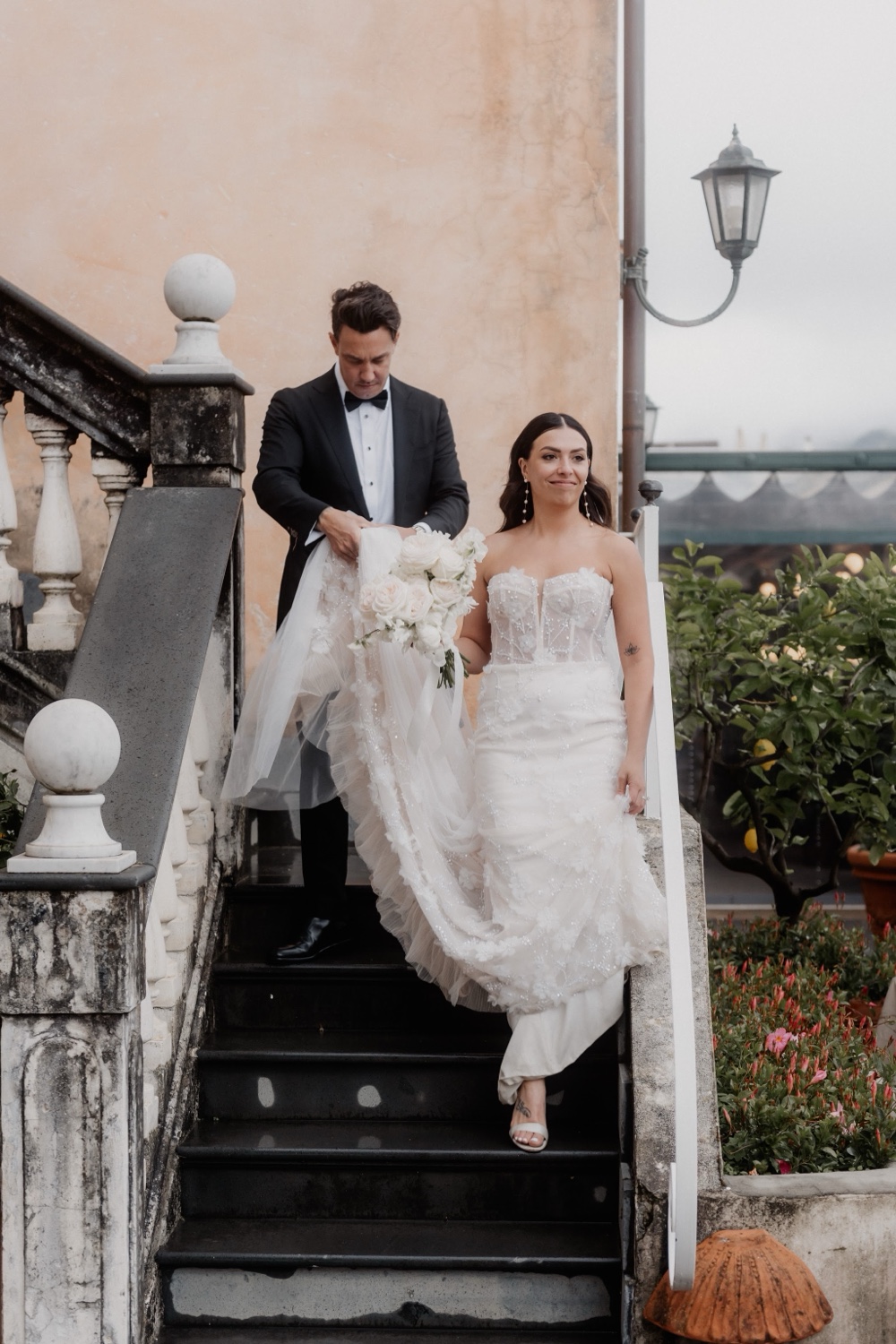 A couple walking down the old stone staircase at Palazzo Avino in Ravello, with lemon trees beside them
