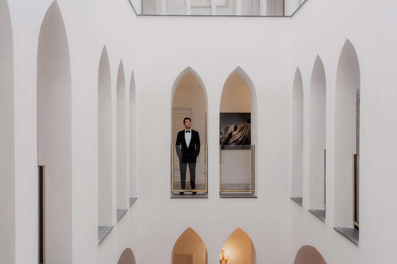 The white arched interior courtyard of Palazzo Avino in Ravello, with a groom standing in one of the pointed arches