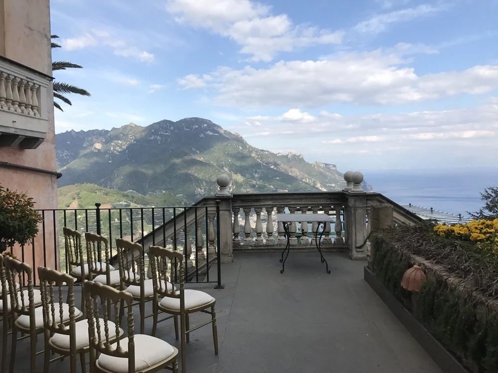The Terrazza Vimini at Palazzo Avino in Ravello, set with gold chairs for a ceremony, with the mountains and the sea beyond