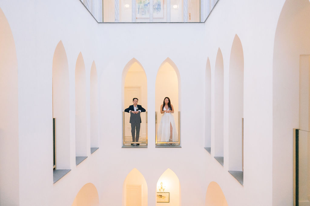 A couple leaning on the balconies of the white arched courtyard at Palazzo Avino in Ravello