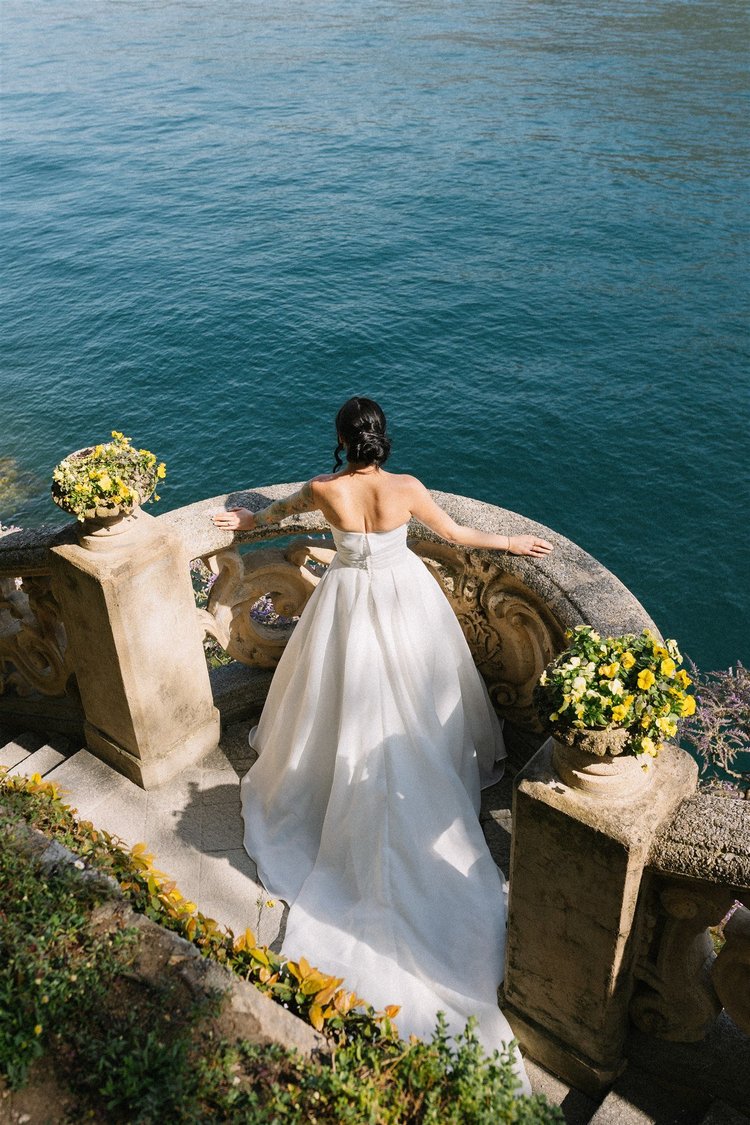 A bride at a stone balustrade over the water