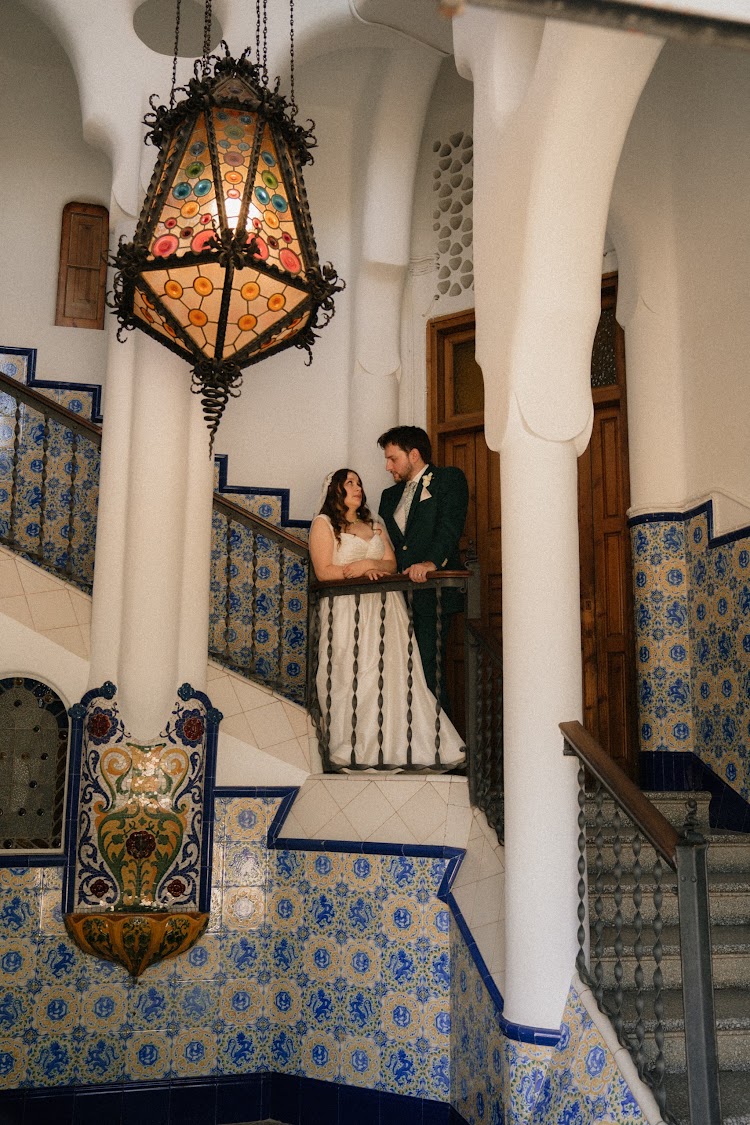 A couple on the blue-and-white tiled staircase inside Bellesguard Tower, a Gaudí building in Barcelona