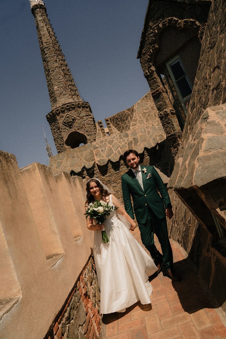A couple on the rooftop terrace of Bellesguard Tower, a Gaudí building in Barcelona, with the spire behind