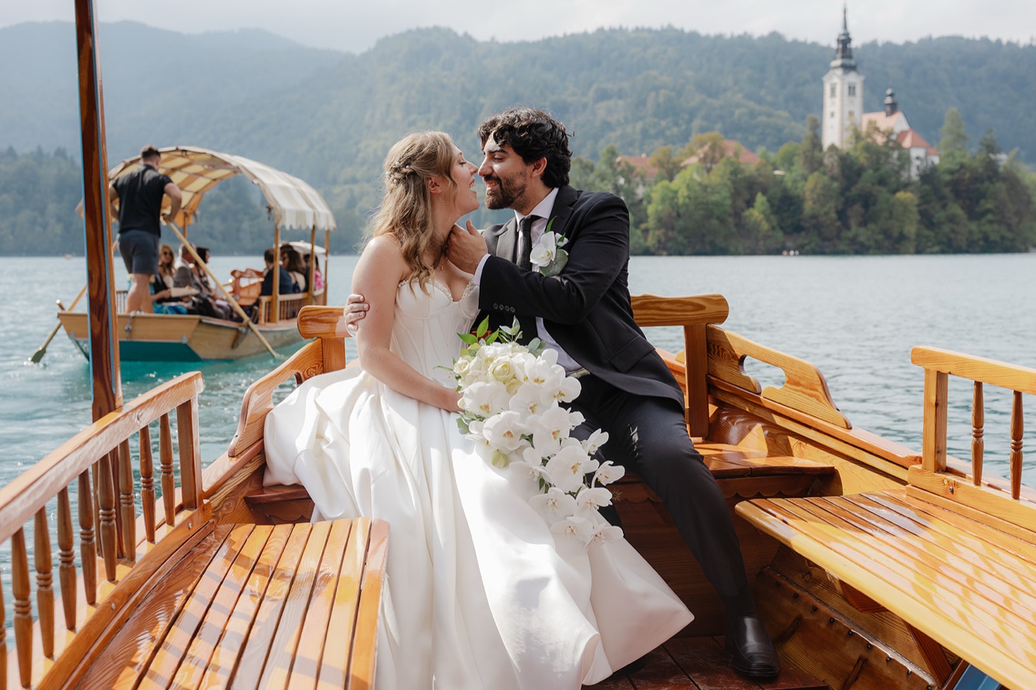 A couple on a Pletna boat on Lake Bled, with Bled Island and its church behind them, Slovenia