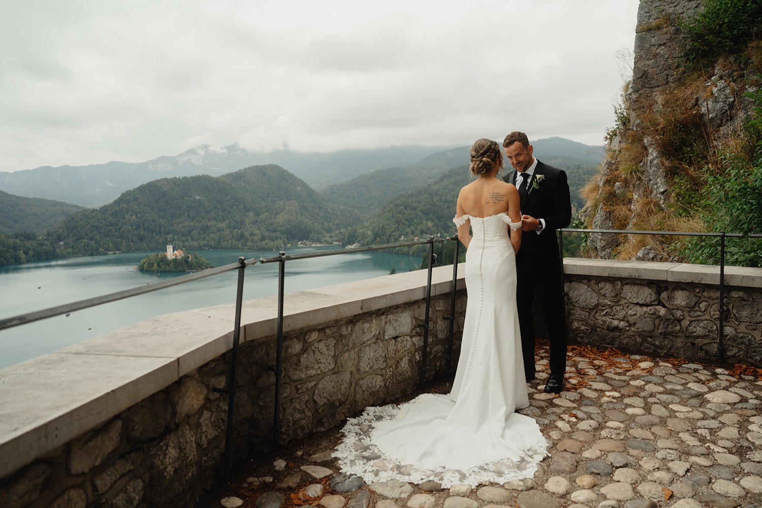 A couple embracing on the stone terrace of Bled Castle, with Lake Bled below, Slovenia