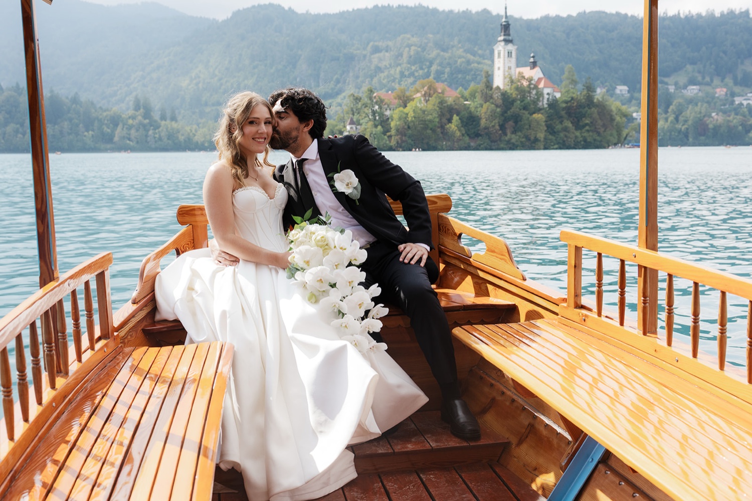 A couple kissing on a Pletna boat in front of Bled Island on Lake Bled, Slovenia