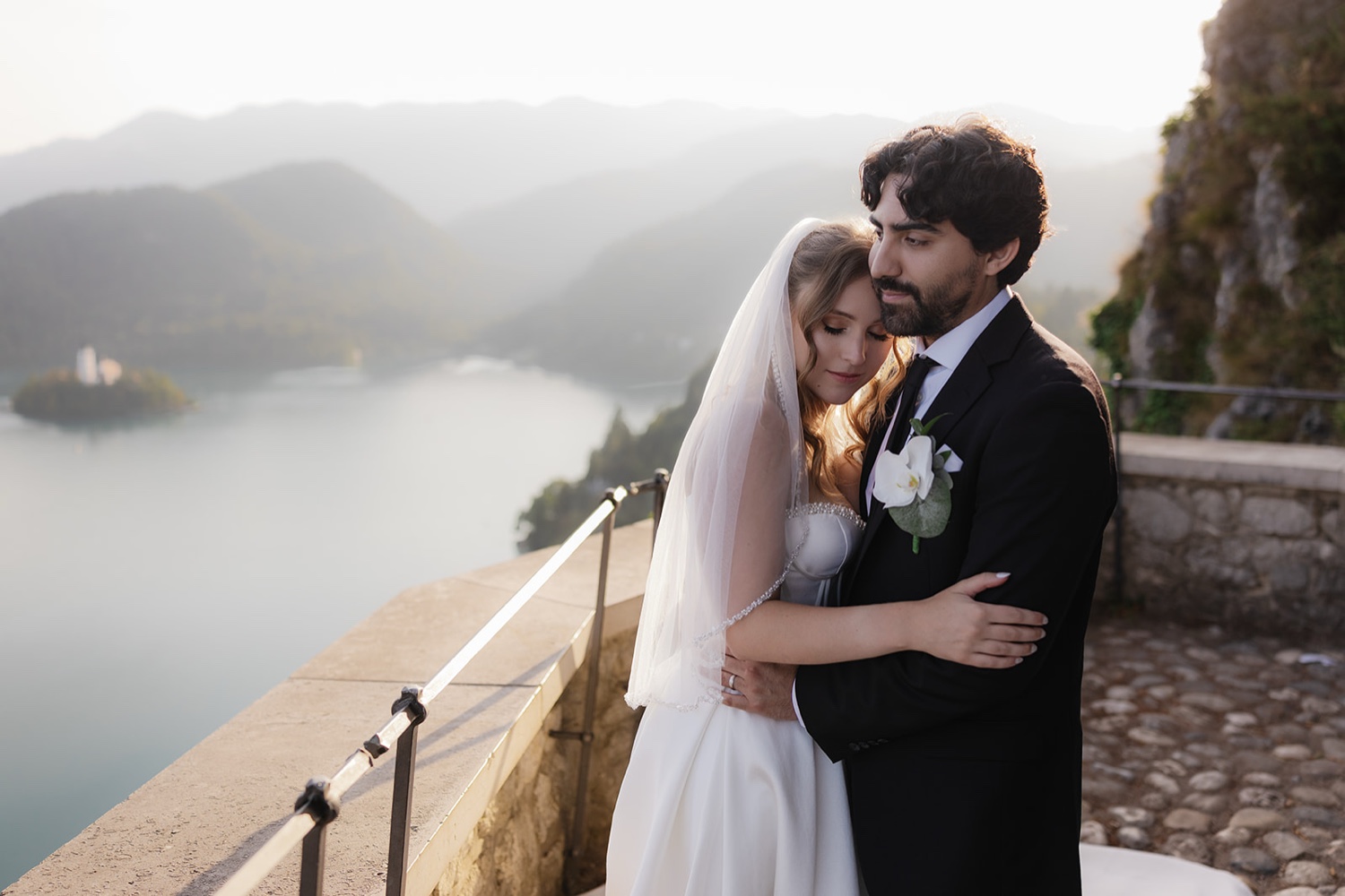 A couple embracing on a terrace above Lake Bled, with the lake and mountains behind, Slovenia