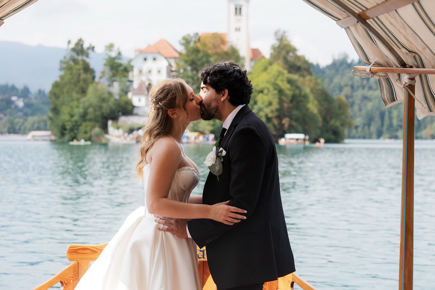A couple kissing on a Pletna boat with Bled Island behind them on Lake Bled, Slovenia