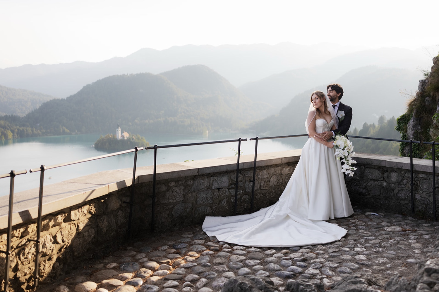 A couple embracing on the terrace of Bled Castle, with Lake Bled and the mountains behind, Slovenia