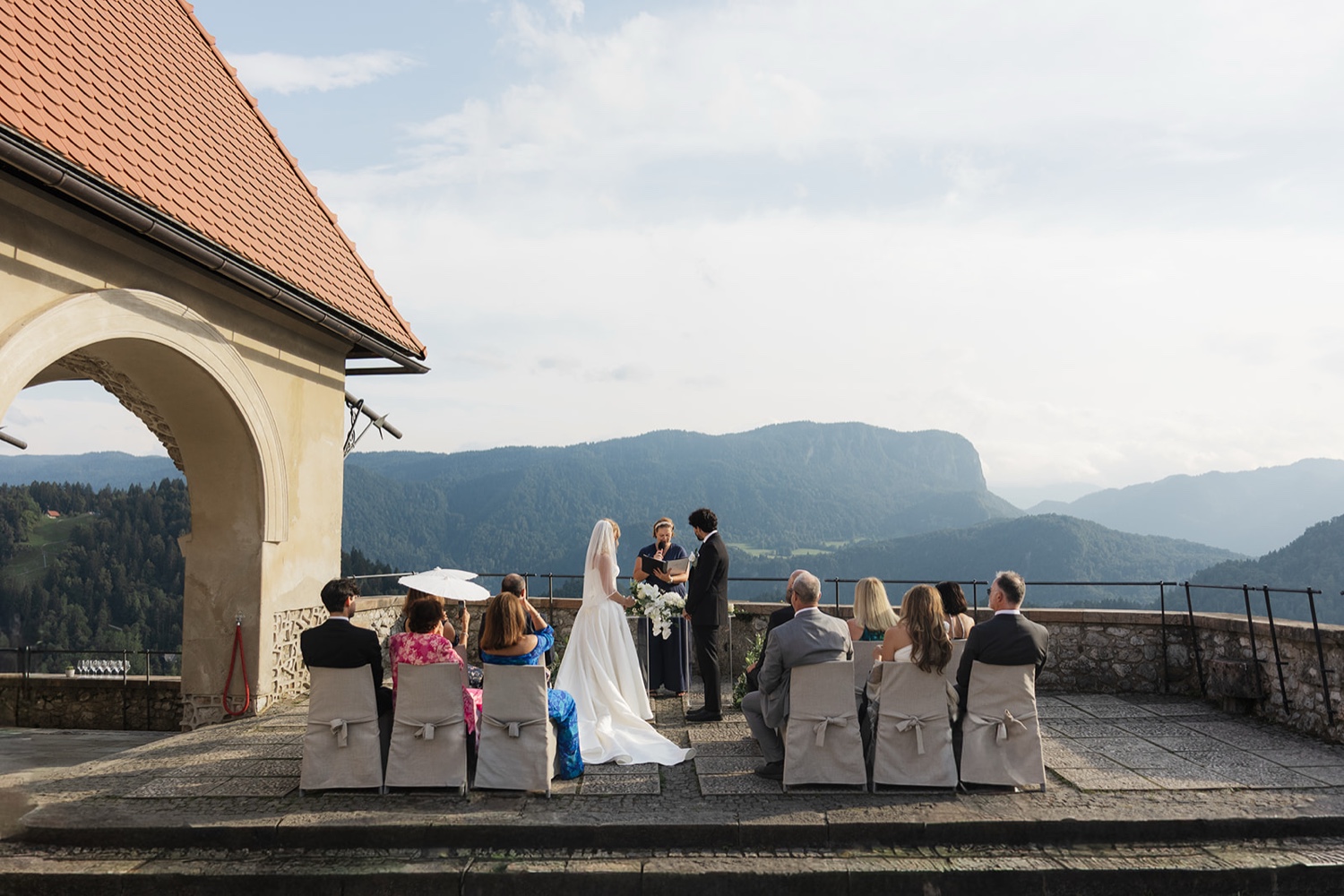 A ceremony on the terrace of Bled Castle, with guests seated and the mountains behind, Slovenia