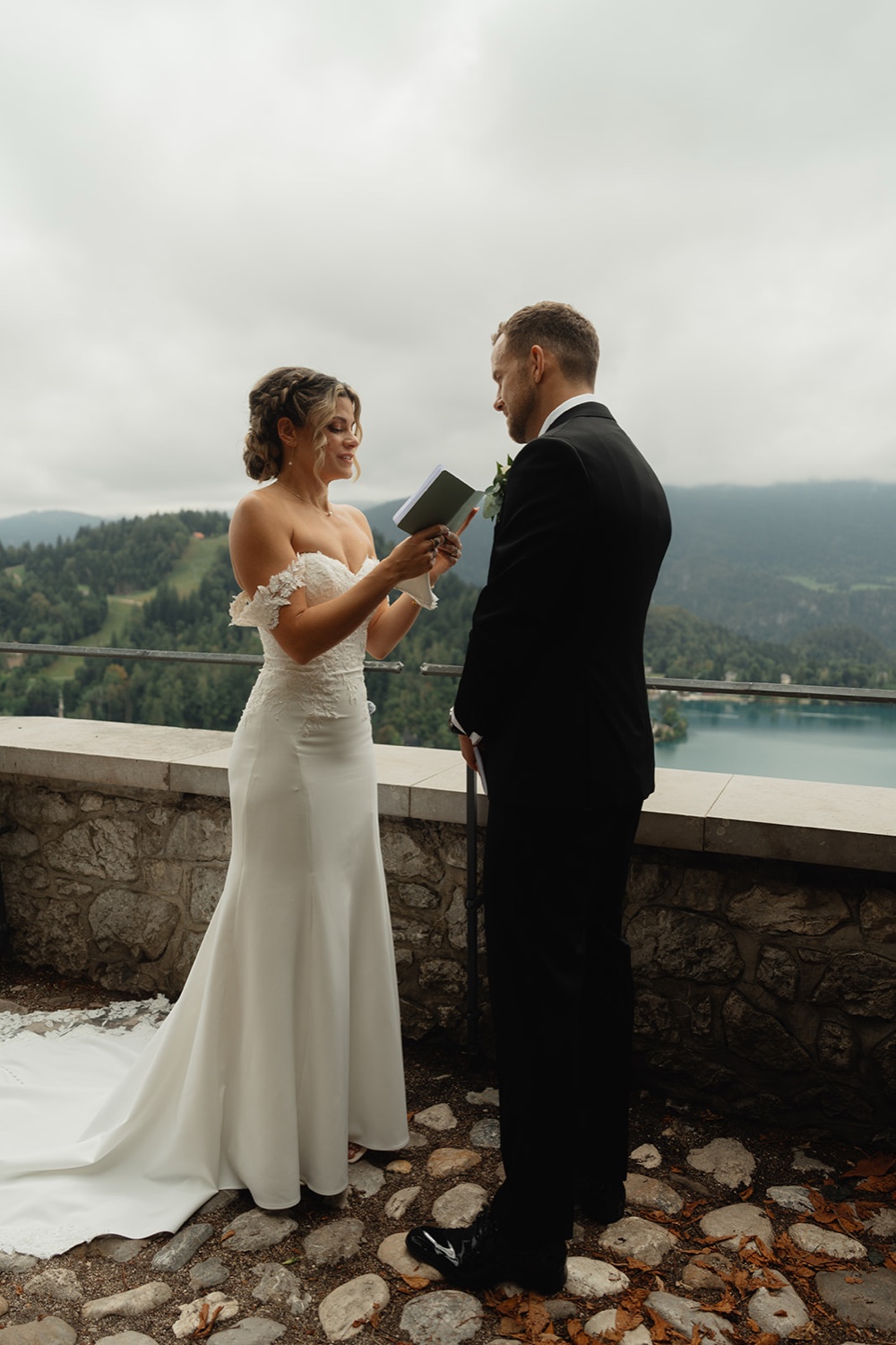 A bride and groom reading their vows on the terrace of Bled Castle, with Lake Bled below, Slovenia