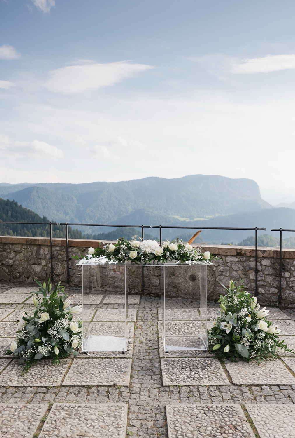 The ceremony set-up on the stone terrace of Bled Castle, with white flowers and the mountains behind, Slovenia