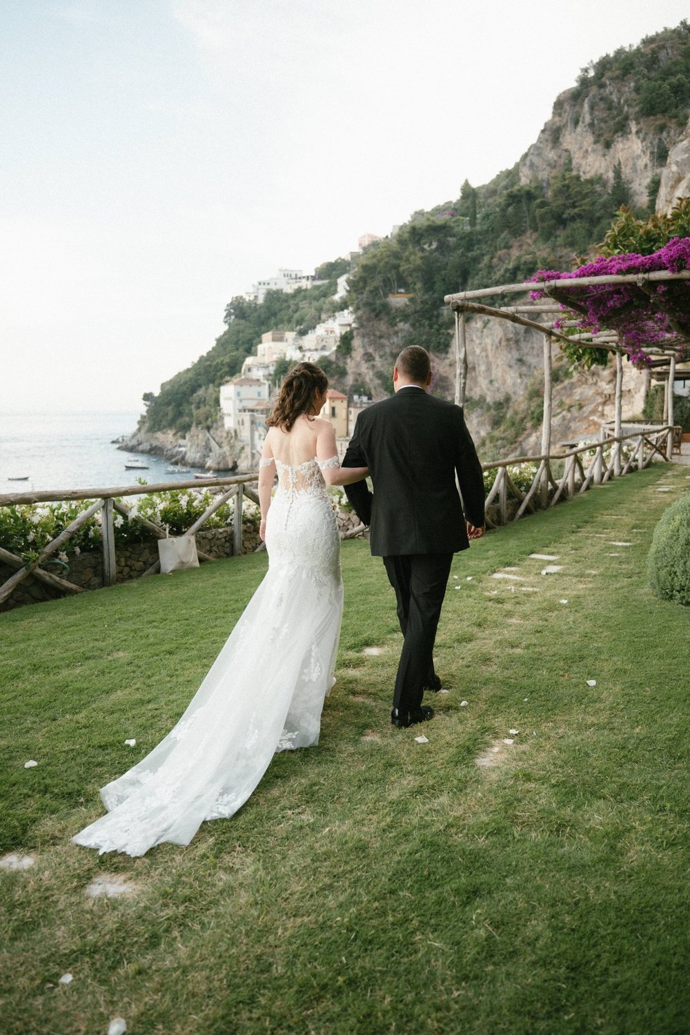 A couple walking across the garden lawn above the sea