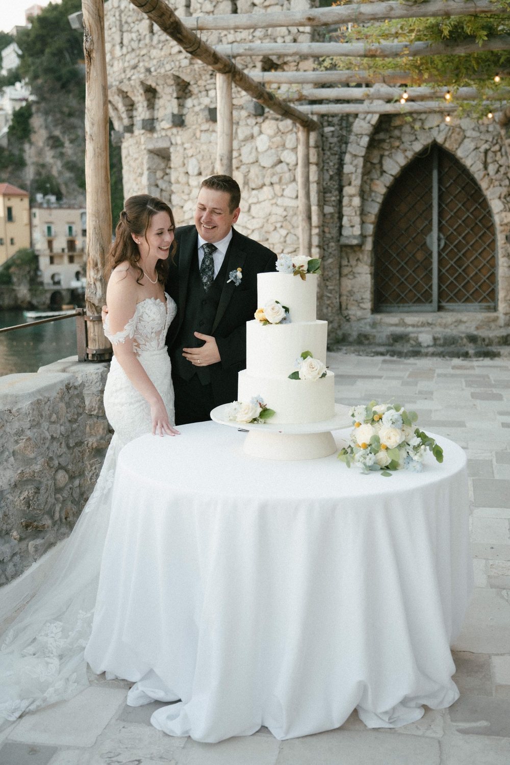 The wedding cake on a table in front of the old stone arches