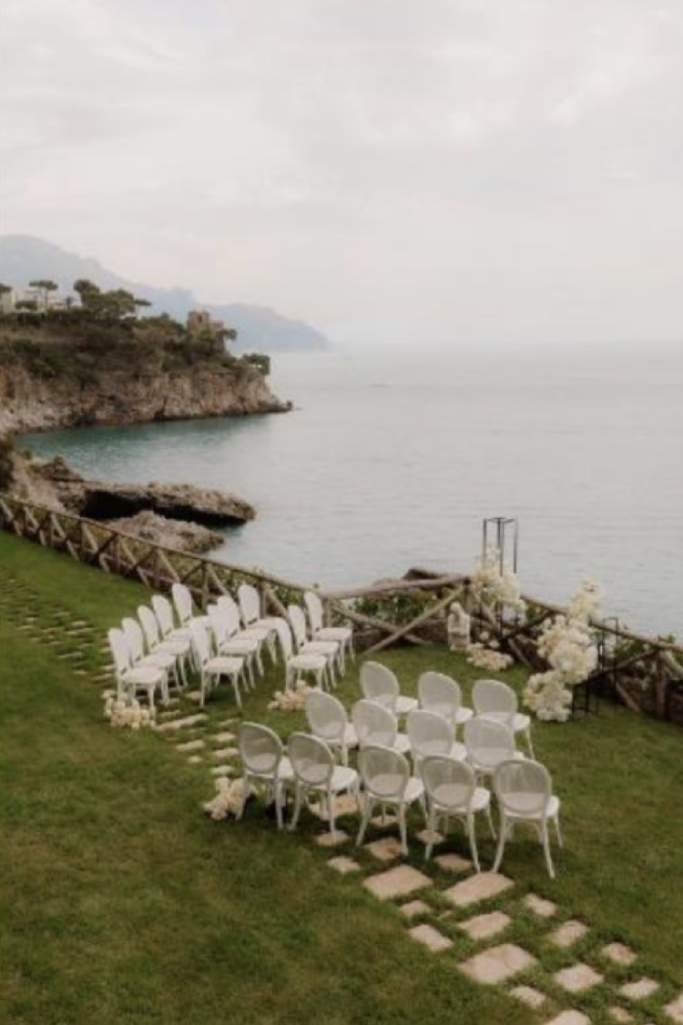 The ceremony location at Borgo Santandrea, with white chairs on the lawn above the sea