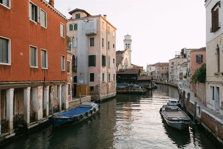 A quiet canal in Venice, lined with boats
