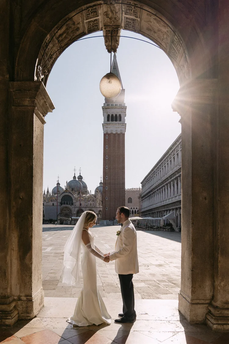A couple walking under the arcades near St Mark’s