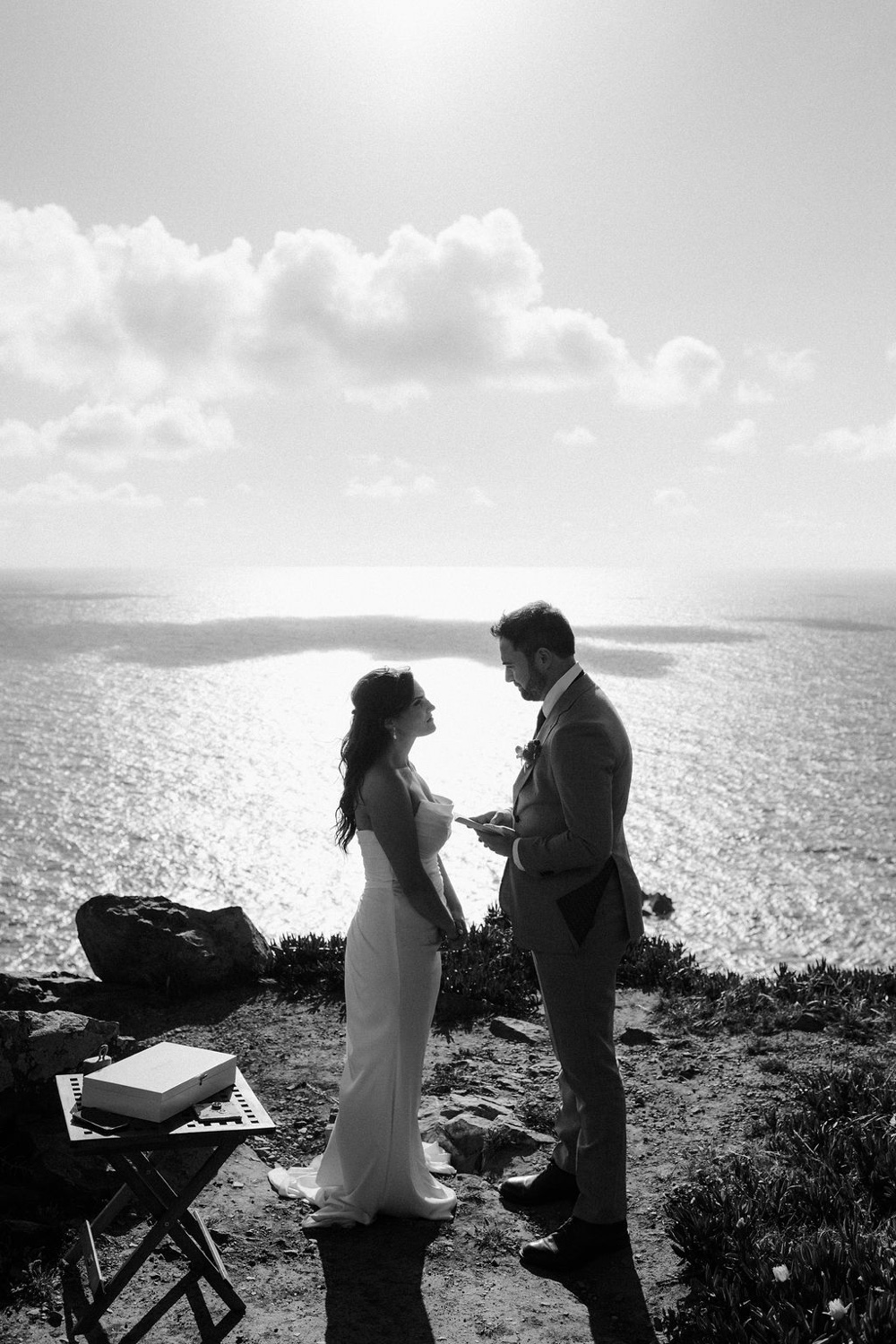 A black and white photo of a couple saying their vows on the cliffs of Cabo da Roca in Sintra, Portugal
