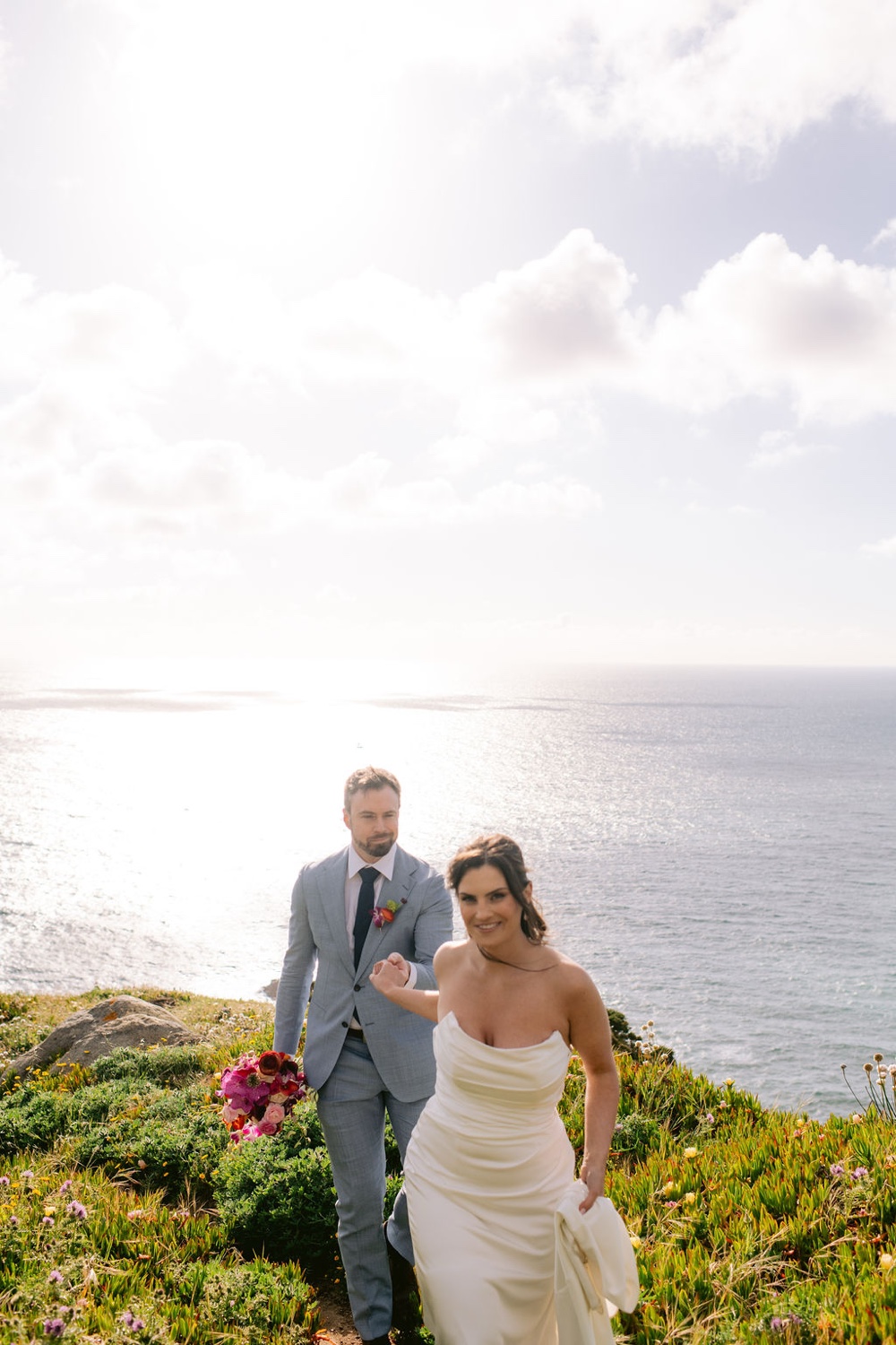A couple walking hand in hand along the clifftop at Cabo da Roca in Sintra, Portugal