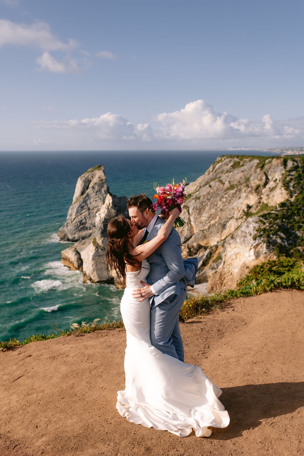 A groom lifting his bride on the cliffs of Cabo da Roca in Sintra, Portugal