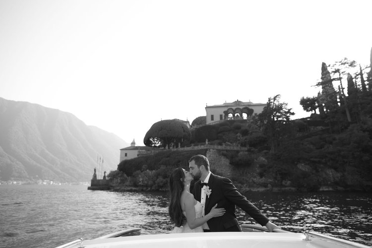 A kiss on the boat in front of a lakeside villa