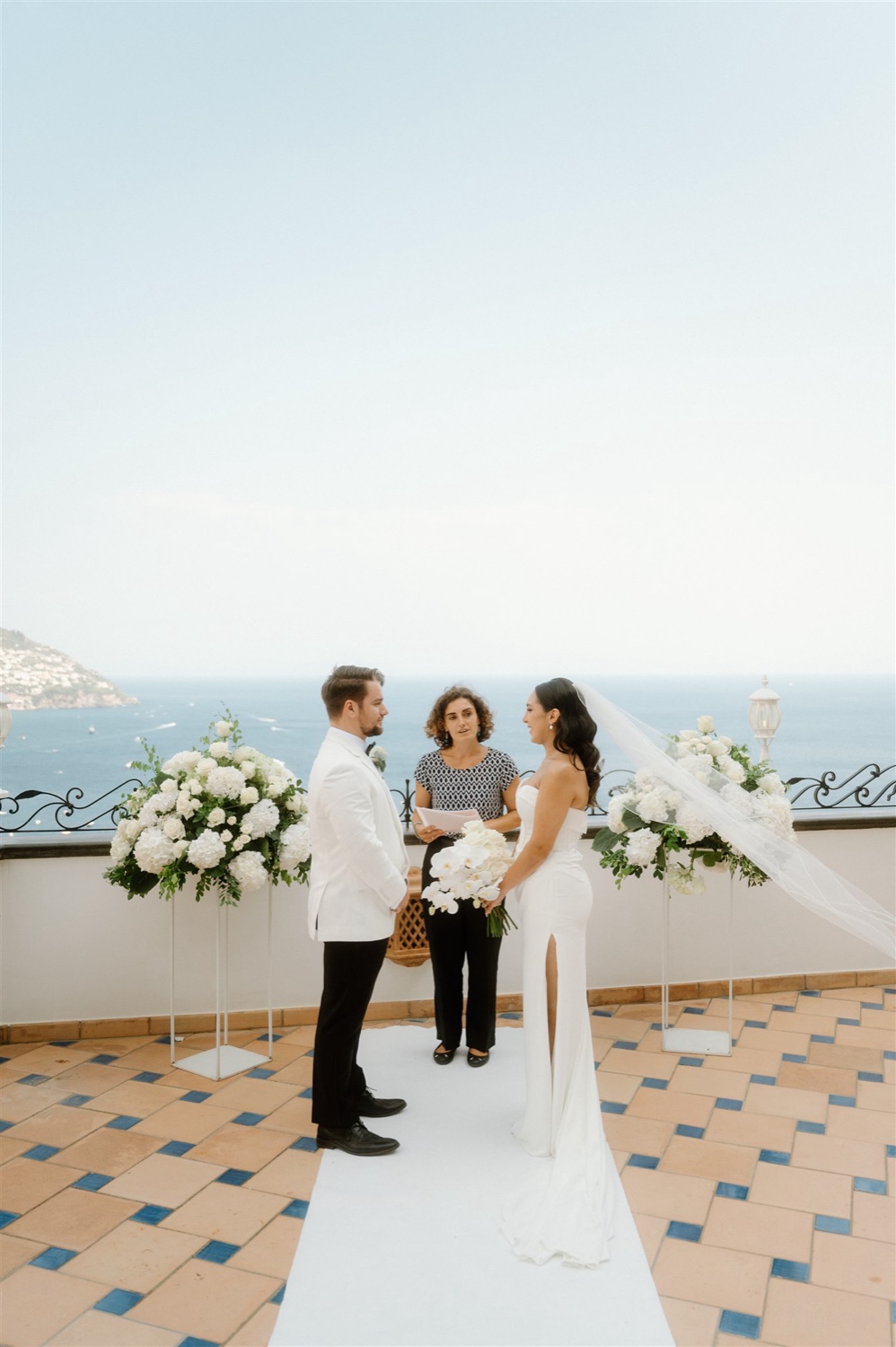 A bride and groom exchanging vows with their celebrant on the rooftop terrace of Hotel Conca d’Oro in Positano