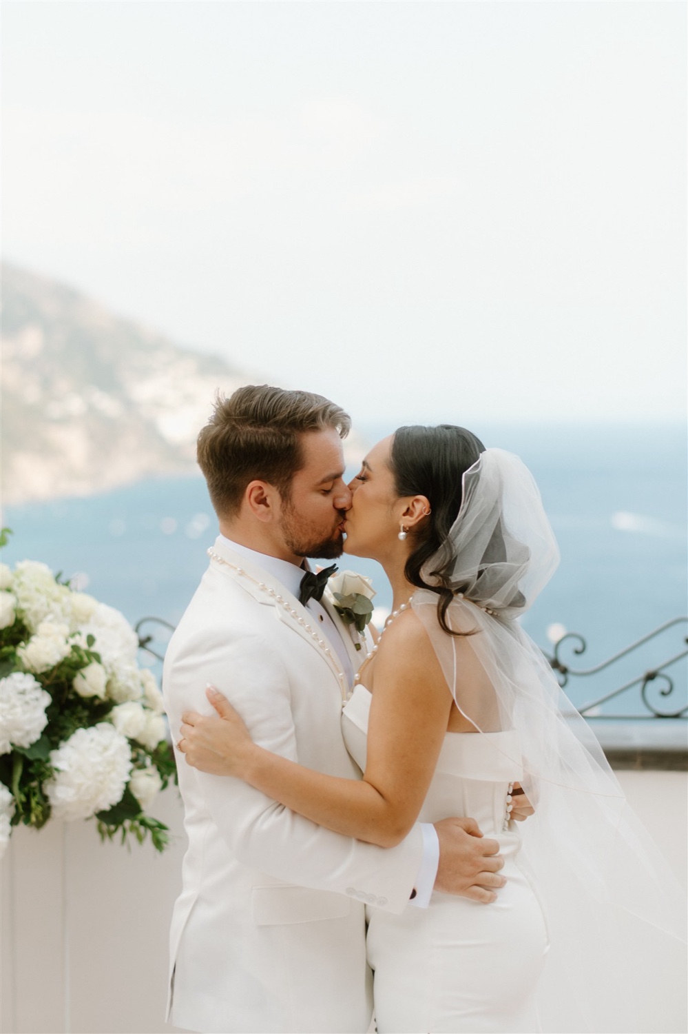 A couple kissing on the rooftop terrace of Hotel Conca d’Oro in Positano, with the sea behind them