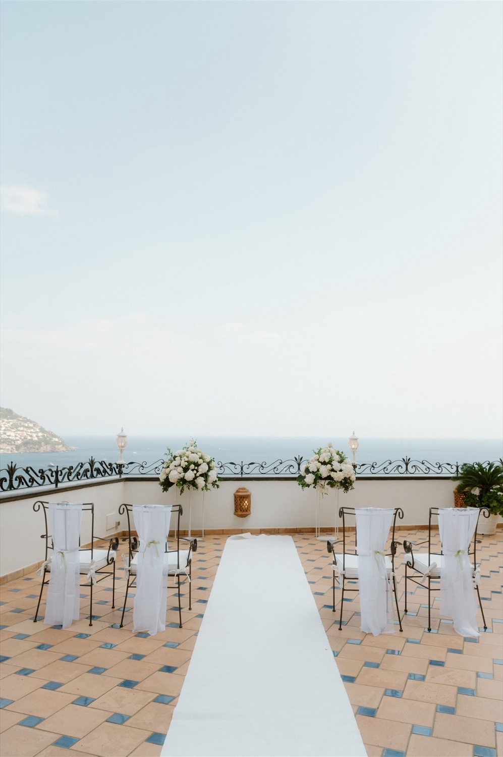 The rooftop terrace of Hotel Conca d’Oro in Positano, set for a ceremony with a white aisle and flowers facing the sea