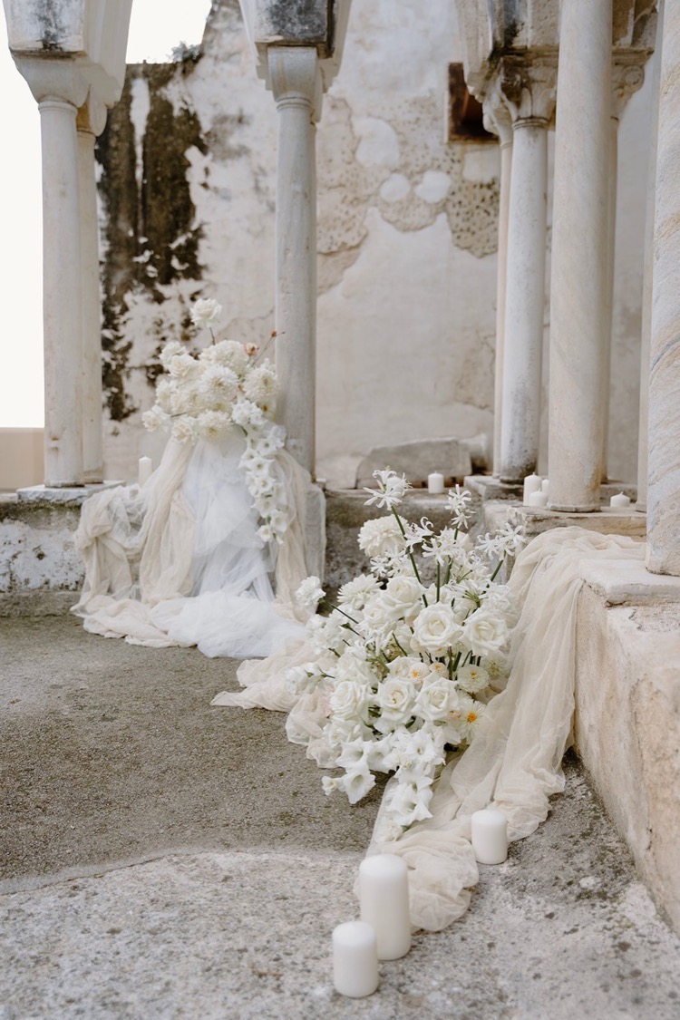 White florals and candles among the columns of the cloister