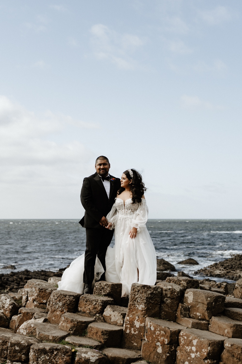 A couple standing together on the basalt columns of the Giant's Causeway, with the sea behind them, Northern Ireland