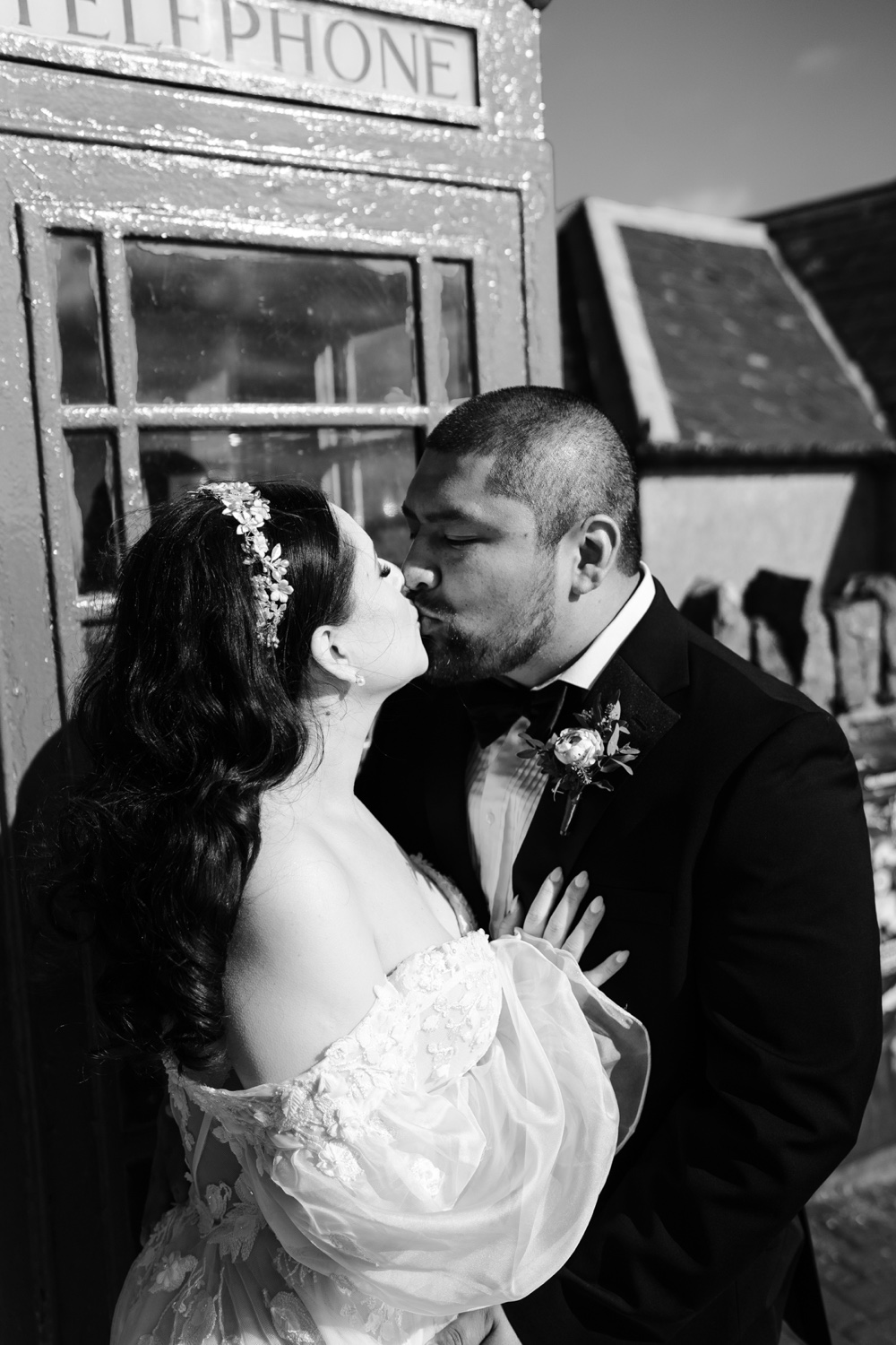 A black and white photo of a couple kissing in front of a red telephone box in Northern Ireland