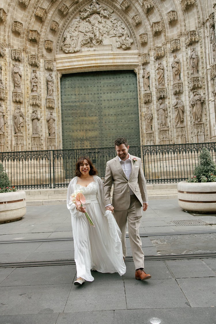 A couple walking hand in hand in front of the Seville Cathedral doors near EME Catedral Mercer