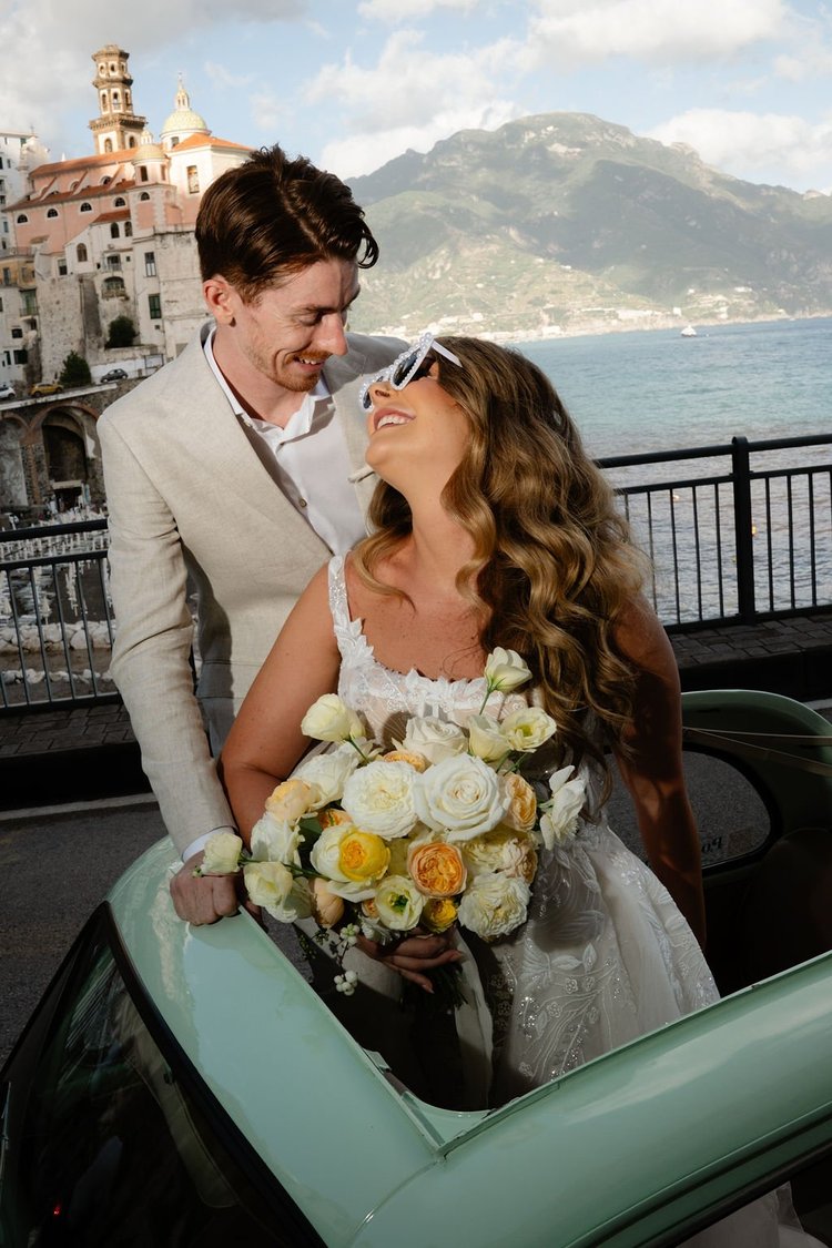 A couple in the vintage car, with the Amalfi Coast behind