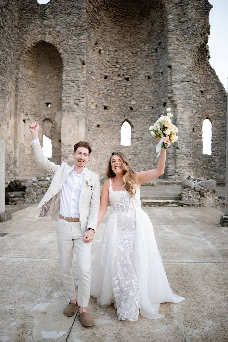 A couple walking through the ruins after their ceremony