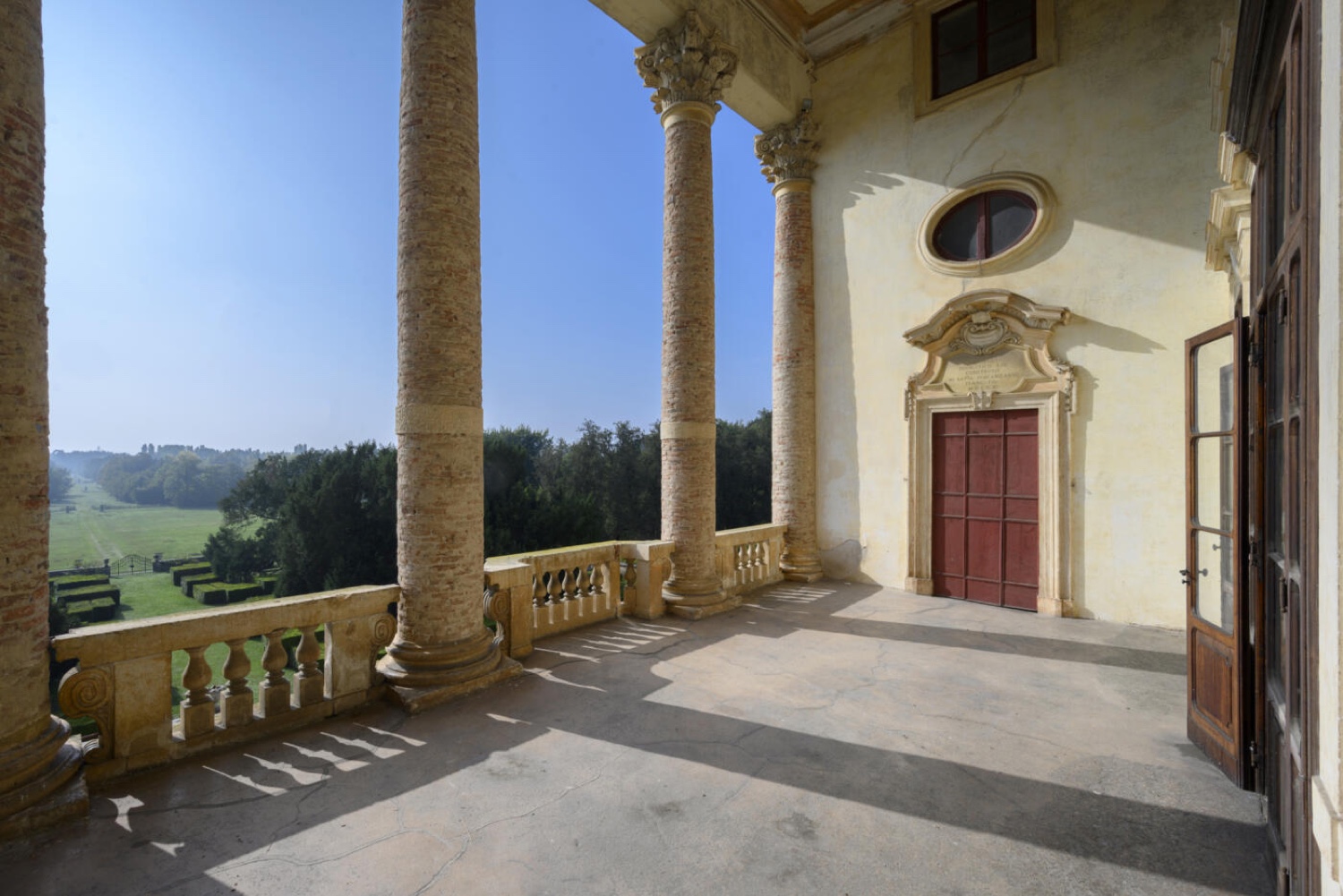 A balcony with stone columns looking out over the countryside at Villa Fracanzan Piovene near Verona