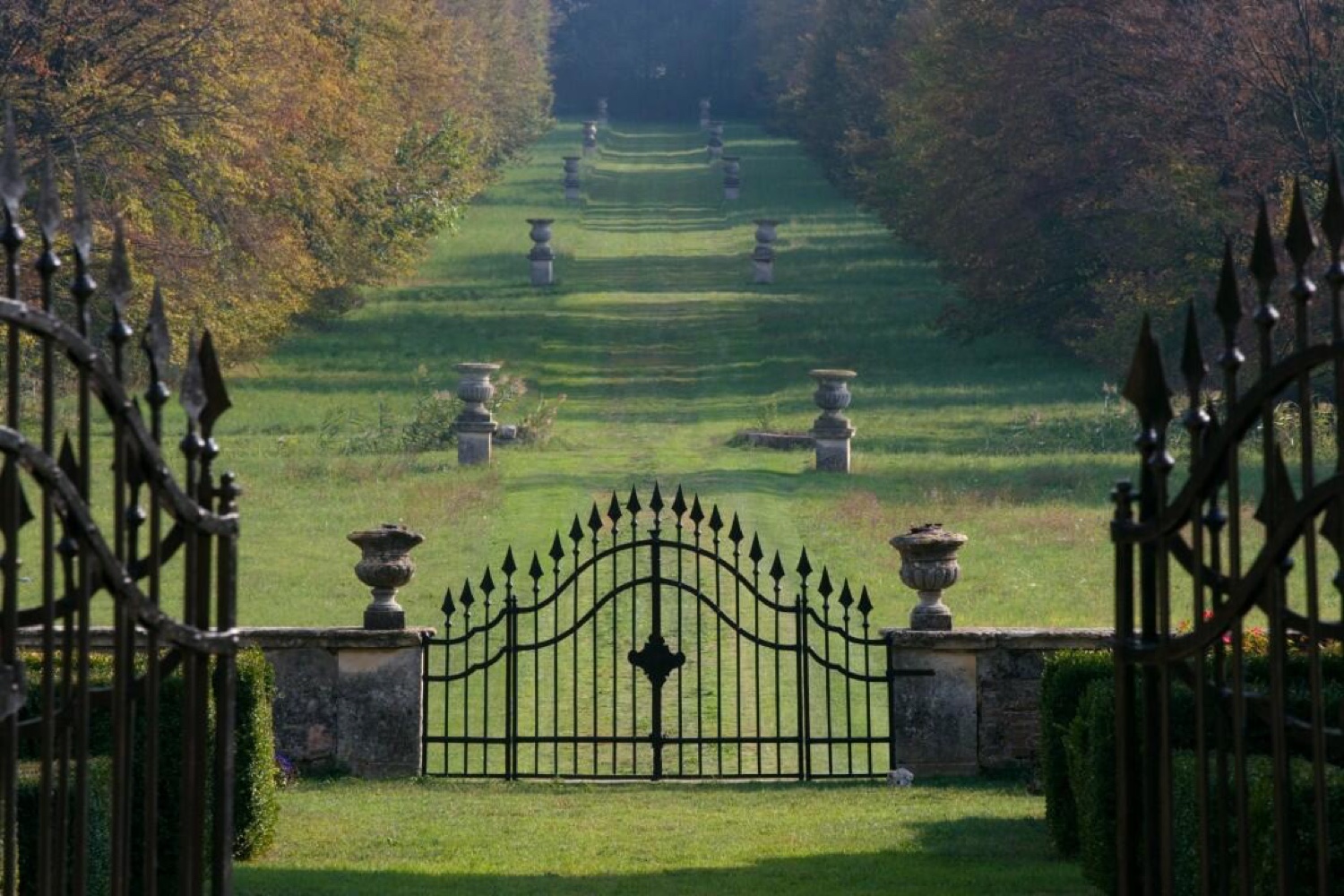 A wrought-iron gate at the end of a long grass avenue in the gardens of Villa Fracanzan Piovene near Verona