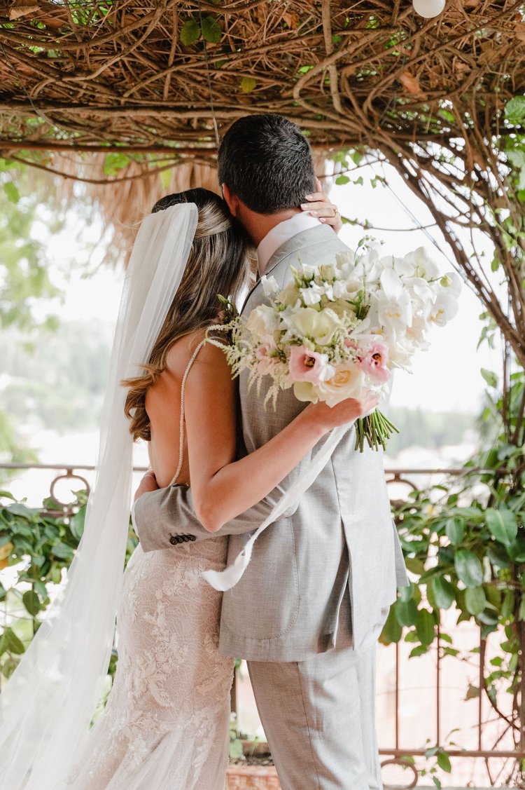 A bride and groom embracing under a leafy pergola during their elopement in Sicily
