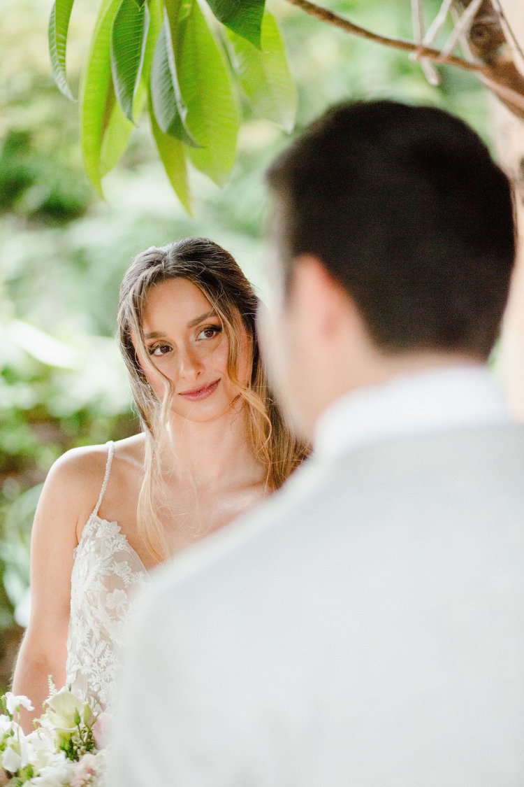 A bride glancing back at her groom surrounded by greenery during an elopement in Sicily