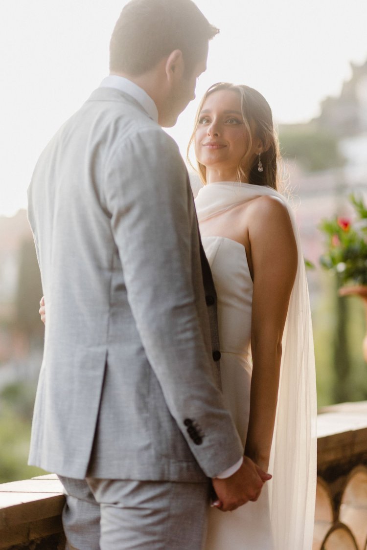 A couple standing close together on a balcony during their elopement in Sicily