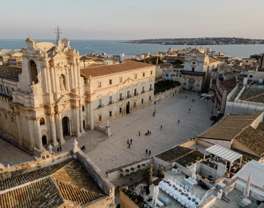 Aerial view of the Terraza Killiche terrace overlooking the baroque cathedral and piazza in Sicily, set up for an elopement aperitif
