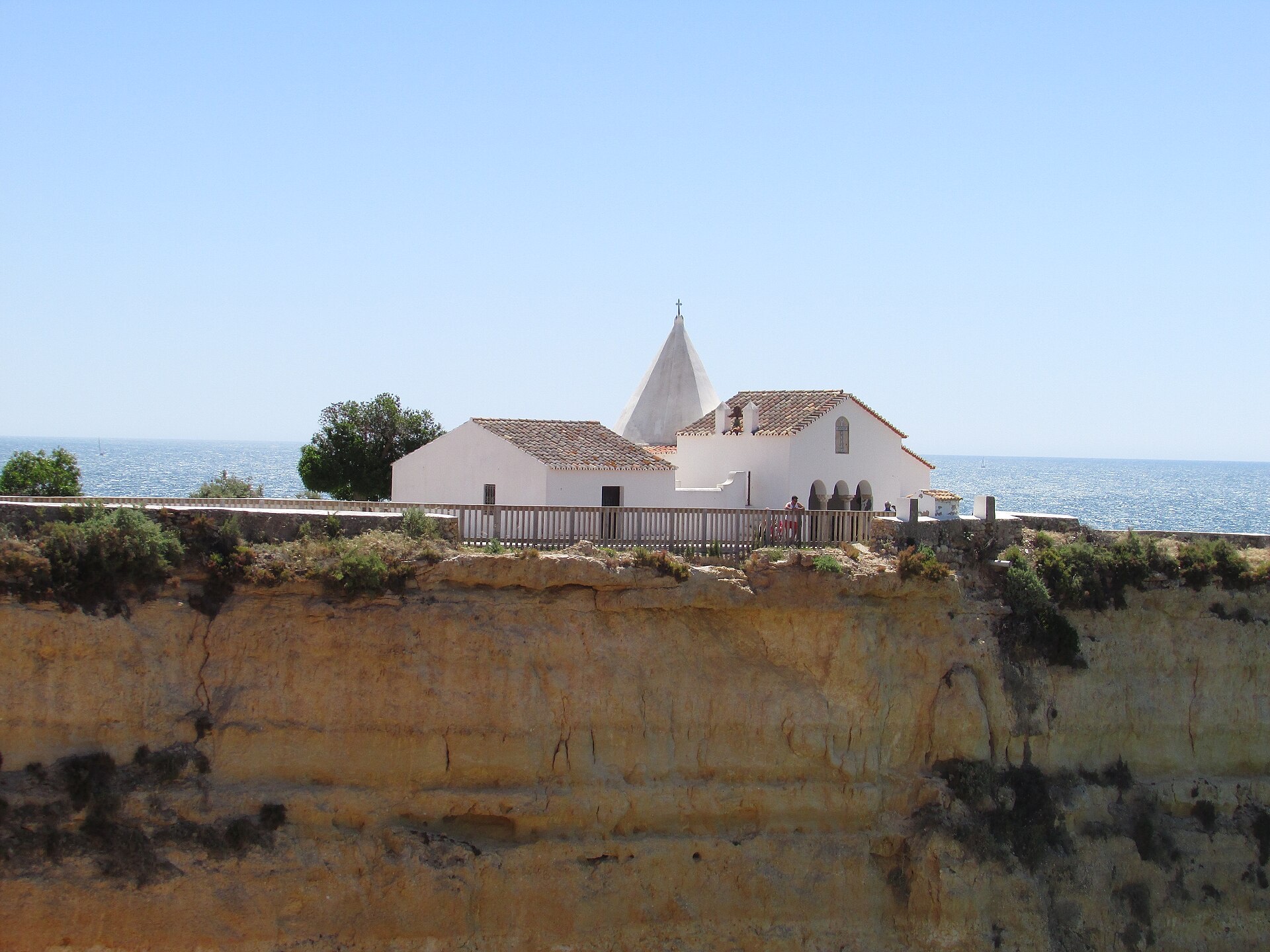 The white chapel of Nossa Senhora da Rocha on its cliff-top square above the Atlantic, with its pointed steeple, in Porches on the Algarve coast