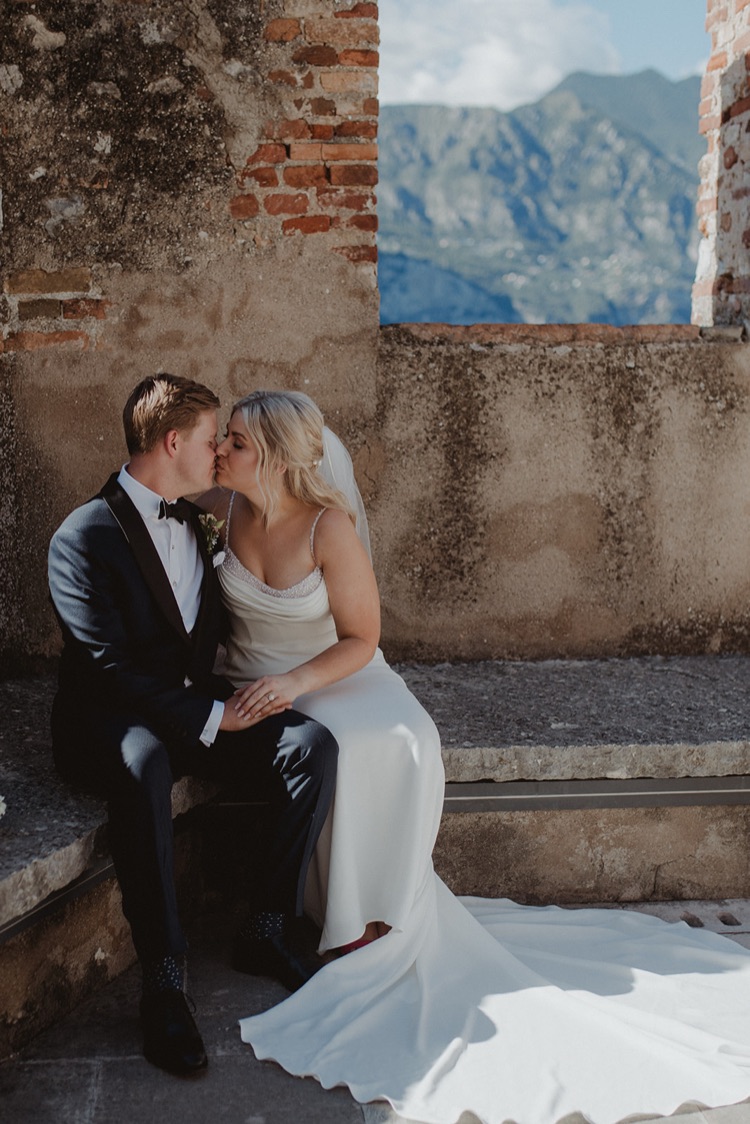 A couple sitting together on the castle walls of Malcesine during their elopement on Lake Garda