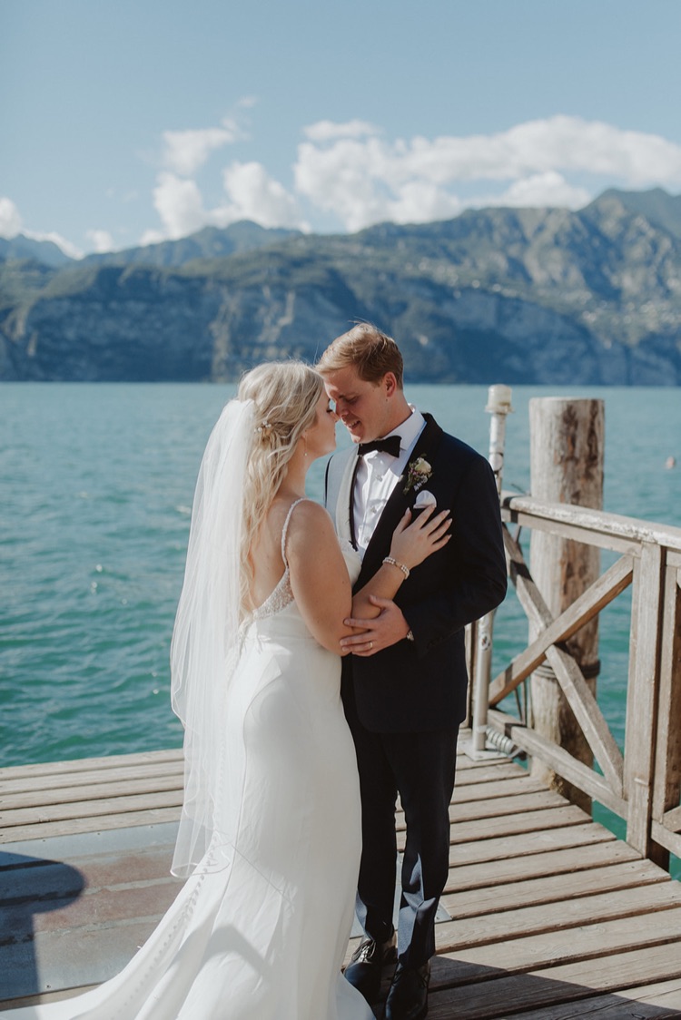 A bride and groom kissing on a wooden jetty on Lake Garda during their elopement