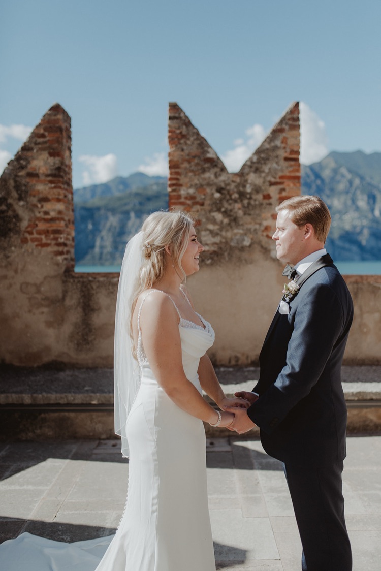 A bride and groom holding hands on the castle terrace in Malcesine during their elopement