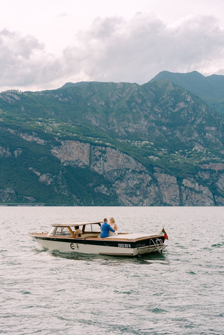 A classic wooden boat on Lake Garda with mountains behind during an elopement in Italy