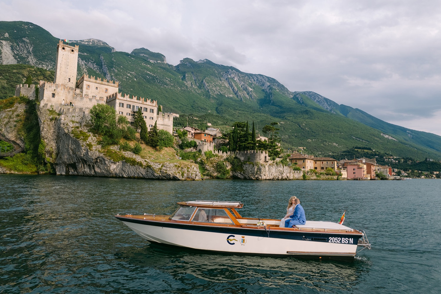 The Scaliger Castle of Malcesine on a cliff above Lake Garda with a boat crossing the water, Italy