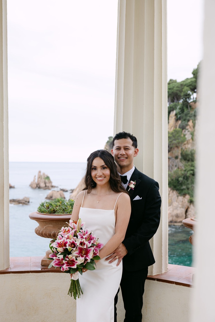 A smiling couple with a pink bouquet between the white columns of the Linnaeus Temple, Marimurtra Botanic Gardens, Costa Brava