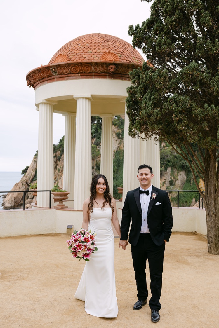 A bride with a pink bouquet beside the Linnaeus Temple at Marimurtra Botanic Gardens, Blanes, Costa Brava